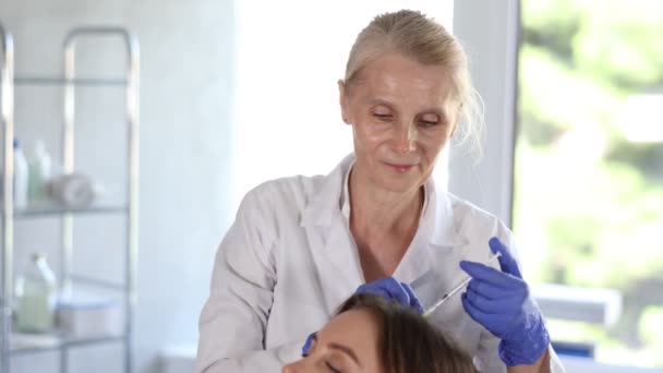 臨床椅子に横たわる若い女性患者が注射方法でヘアケアを受ける — ストック動画