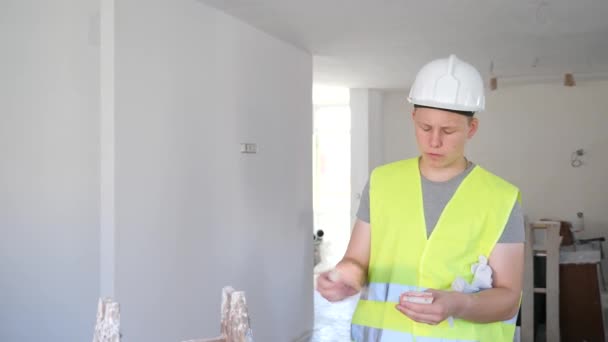 满意的年轻人穿着背心 头戴安全帽 手里拿着一大堆现金 在建筑工地找到第一份兼职工作 男孩拿到了他的第一份工资 — 图库视频影像