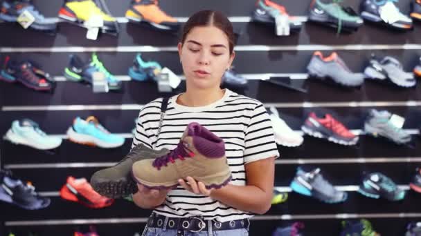 Νεαρή Κοπέλα Στο Κατάστημα Αθλητικών Επιλέγει Παπούτσια Πεζοπορίας Για Πεζοπορία — Αρχείο Βίντεο