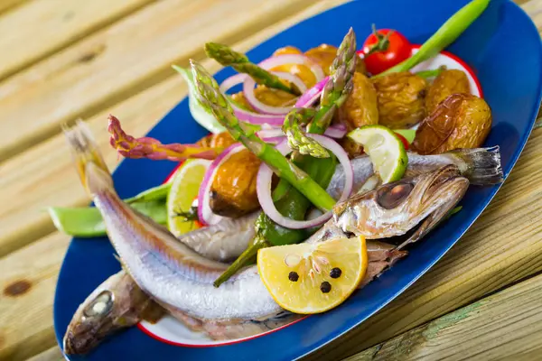 Delicious fish dish - stewed in white wine Blue Whiting fish with potatoes and pea pods on plate