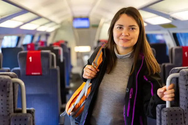 Glimlachende Vrouwelijke Backpacker Reist Trein Staat Gangpad Tussen Rijen Stoelen — Stockfoto