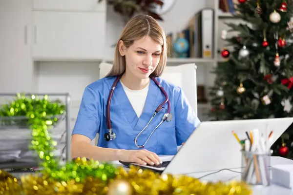 Positive Woman Doctor Working Medical Office Using Laptop Computer Christmas — Zdjęcie stockowe