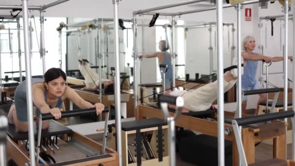 Concentrated Young Asian Girl Performing Set Pilates Exercises Reformer Group — Stock Video