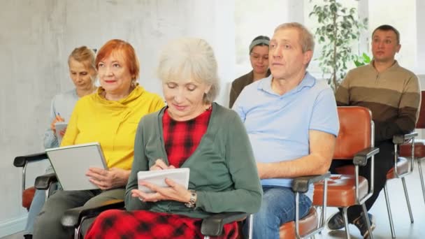 高齢者のための言語コースで注意深く耳を傾け ノートを取るポジティブな興味のある高齢女性 — ストック動画
