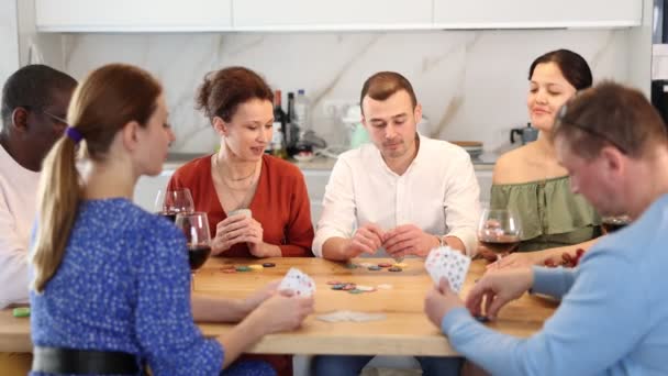 年轻人与一群不同国籍的朋友在厨房桌旁悠闲的家庭氛围中沉醉在友好的扑克游戏中 高质量的4K镜头 — 图库视频影像