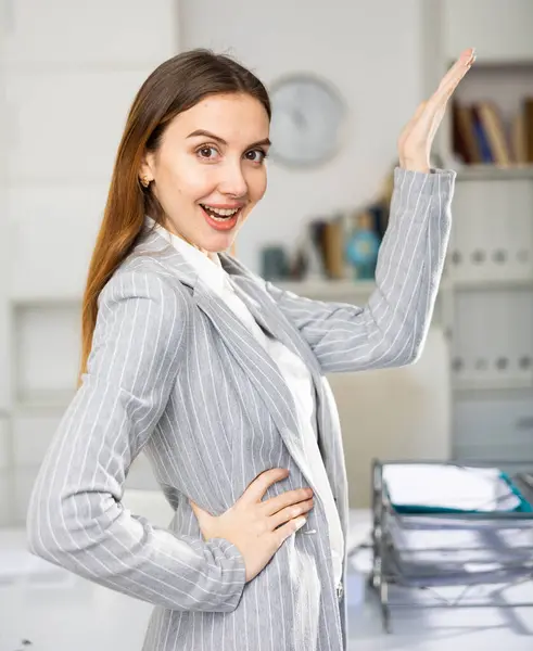 オフィスに立って何かを指差す幸せなビジネス女性の肖像画 — ストック写真