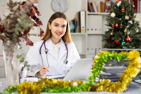 Joven Mujer Médica Caucásica Sentada Mesa Oficina Decorada Durante Navidad — Foto de Stock