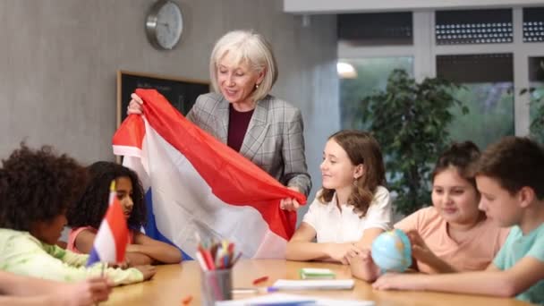 友好的中学教师在课堂上授课 向学生们讲述荷兰的历史 手中拿着荷兰国旗 高质量的4K镜头 — 图库视频影像