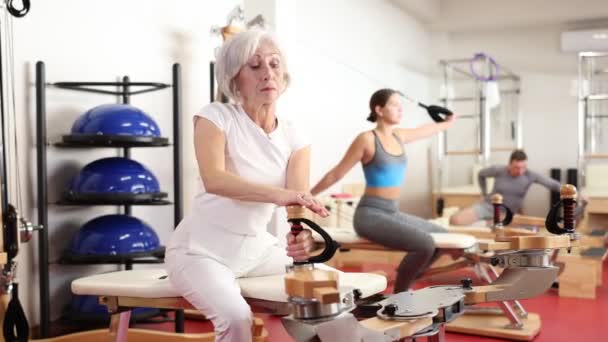 Siłowni Starsza Kobieta Wykonuje Ćwiczenia Pilates Schudnąć Przynieść Mięśnie Ramion — Wideo stockowe