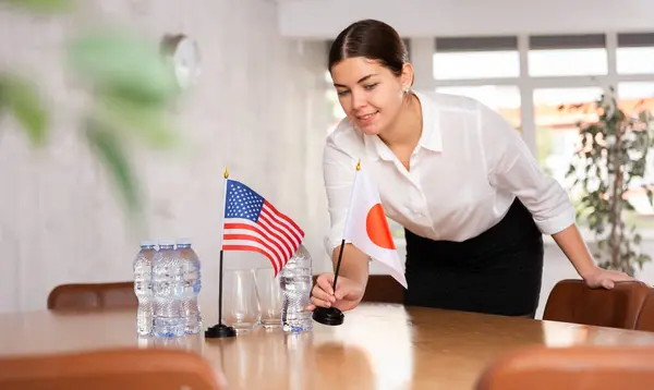 stock image Young woman setting up flags on table for international negotiations between usa and japan