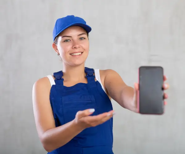 Młoda Dziewczyna Niebieskim Kombinezonie Pokazuje Ekran Nowoczesnego Smartfona — Zdjęcie stockowe