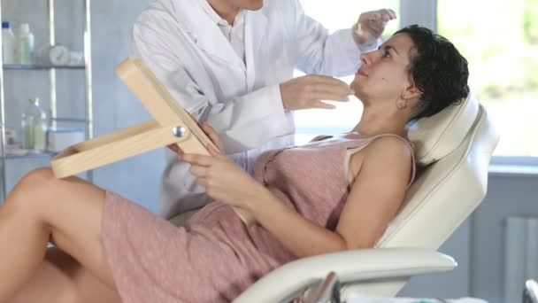 Esteticista Experiente Masculino Dando Consulta Paciente Mulher Com Espelho Clínica — Vídeo de Stock