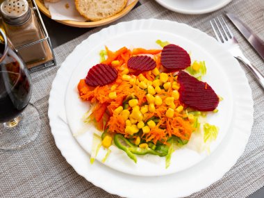 Appetizing light vegetable salad made from corn, sliced beetroot, bell pepper, grated carrots and onions clipart
