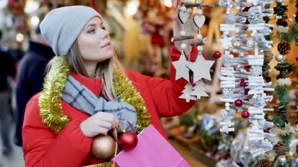 Молодая Улыбающаяся Женщина Выбирает Рождественские Украшения Открытом Рынке Высококачественные Fullhd — стоковое видео