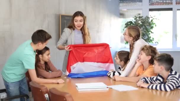 学校でオランダの旗を記述する教育を注意深く見ている小学生のグループ — ストック動画