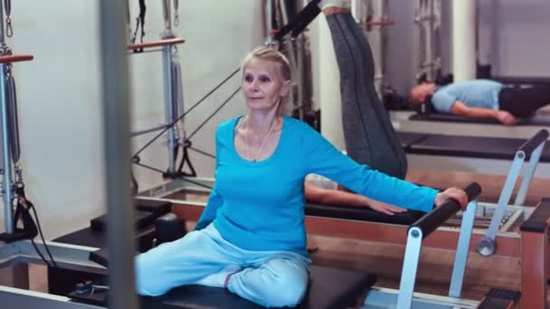 Koncentrovaná Vyspělá Žena Sportovním Oblečení Tahání Ruku Pásu Pilates Reformovací — Stock video