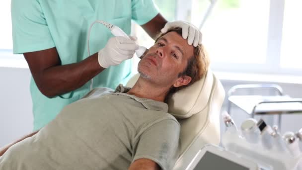 Europejczyk Leży Kanapie Podczas Zabiegu Pielęgnacji Twarzy Dermatolog Kosmetolog Stosujący — Wideo stockowe