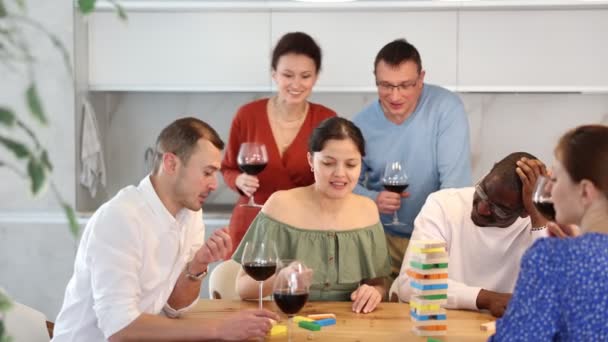 居心地の良いキッチンセッティングでワインを集めながら 自宅でさまざまな国籍の友人と遊ぶアジアの女性の笑顔 高品質の4K映像 — ストック動画