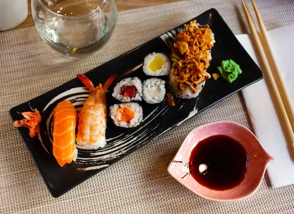 日本の伝統的な寿司皿 具材は ニギリとサーモンとエビ 巻き寿司に揚げ玉ねぎをトッピング — ストック写真
