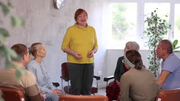 感情用事的老年女家庭教师为坐在礼堂的一群老年人开办教育课 — 图库视频影像