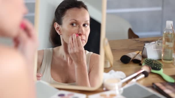 毎日の美容ルーチンに従事する大人の女性は 頬骨にスポンジアプリケーターを使用して顔の形をハイライトし 家庭で虚栄心ミラーの前に暖かいアンダートーンを作成します — ストック動画