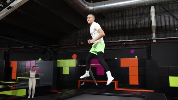 Trambolinde Zıplayan Neşeli Genç Adam Kapalı Bir Eğlence Parkının Renkli — Stok video