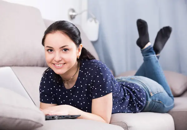 家でソファに横たわっている間 ブルネットの女性はラップトップでリラックス — ストック写真