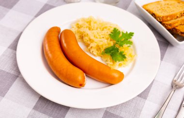 Appetizing sausages with side dish of sauerkraut clipart