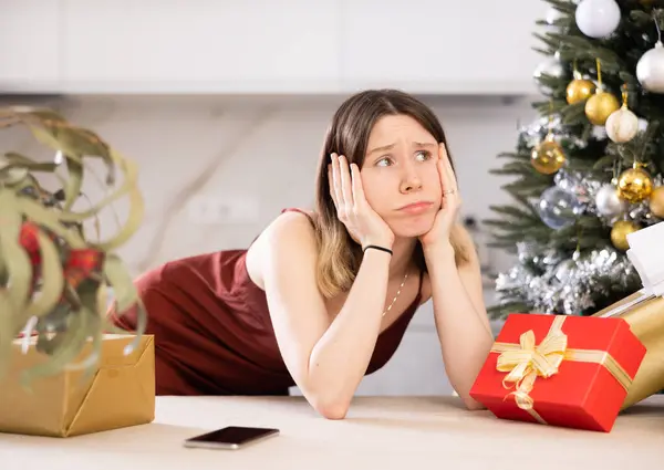 プレゼント付きクリスマスツリーの背景に自宅で悲しい若い女性の肖像画 ストックフォト