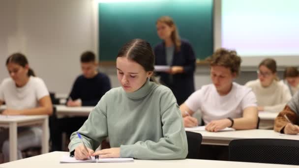 Konsentrert Tenåringsjente Sitter Ved Skrivebordet Studerer Klasserommet – stockvideo