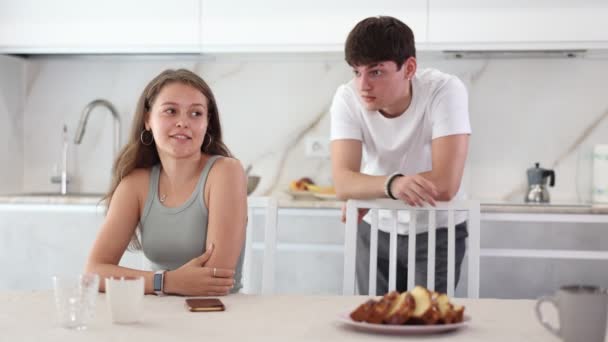 当她男朋友站在厨房后面和她争吵时 可怜的小女孩坐在桌旁 — 图库视频影像