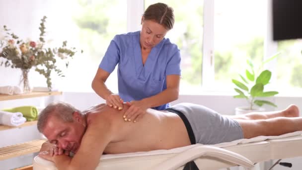 Masseurin Mittleren Alters Gibt Männlichen Patienten Die Massagetisch Liegen Eine — Stockvideo