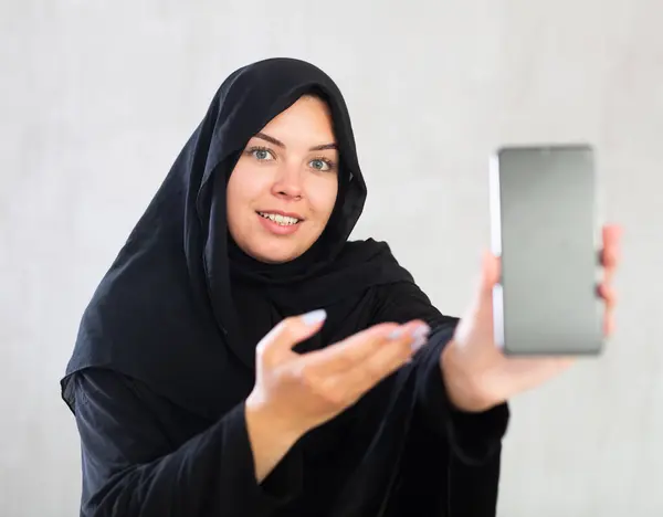 Eine Lächelnde Muslimin Traditionellen Schwarzen Hijab Zeigt Den Leeren Smartphone — Stockfoto