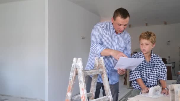 Padre Junto Con Hijito Revisando Planos Antes Renovar Una Habitación — Vídeo de stock