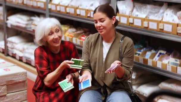 Duas Mulheres Juntas Escolhem Cobertura Multicolorida Amostras Uma Loja Especialidades — Vídeo de Stock