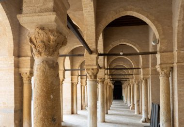 Corridor with arched stone colonnade encircling inner courtyard of Mosque of Uqba in Tunisian city of Kairouan. Traditional Islamic architecture clipart