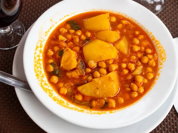 Traditional Spanish dish is cod stewed in tomato sauce with potatoes and chickpeas. Hearty lunch, warming in cold season