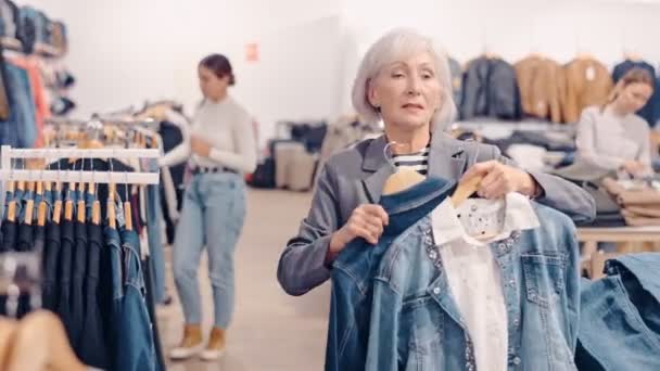 Літня Жінка Покупець Вибирає Джинсову Куртку Магазині Одягу — стокове відео
