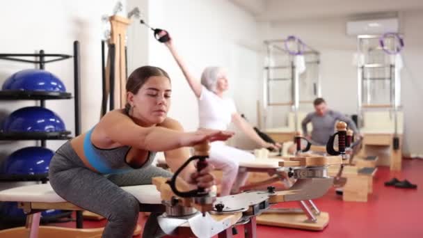 Young Woman Sportswear Stretches Her Arms Shoulders Using Pilates Machine — Stock Video