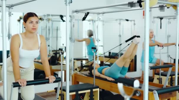 Jovem Mulher Positiva Concentrando Exercício Alongamento Cama Equipamento Pilates Estúdio — Vídeo de Stock
