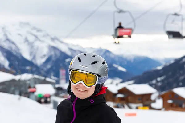 スキーリゾートで冬休みを過ごす若い女性 スキーヘルメットでポーズし バックグラウンドで雪で覆われた山で屋外ゴーグル — ストック写真