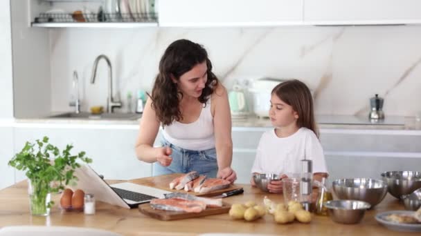 Γοητευμένη Μητέρα Και Κοριτσάκι Ασχολούνται Ψήσιμο Σολομού Στην Κουζίνα Συμβουλεύοντας — Αρχείο Βίντεο