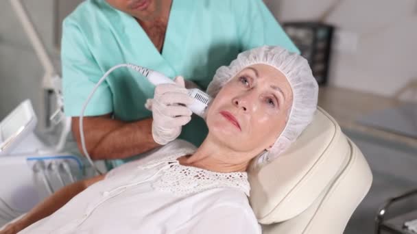 Jistý Kosmetolog Provádějící Aging Obličejovou Terapii Pro Starou Klientku Klinice — Stock video