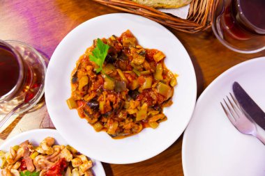 Saksuka, grilled turkish eggplants with tomato sauce in a white ceramic plate clipart