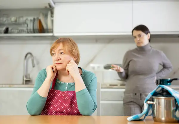 stock image Adult woman in apron and young woman in casual clothes during family quarrel in kitchen