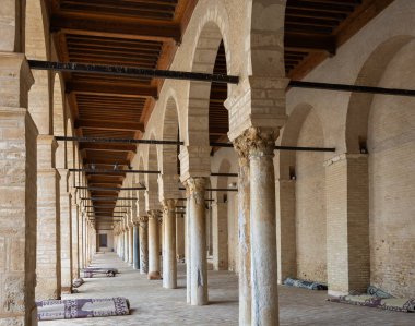 distinctive living arcade with arches supported by Corinthian columns surrounding the courtyard of the Grand Mosque of Kairouan in Tunis, reflecting the art of Islamic architecture clipart