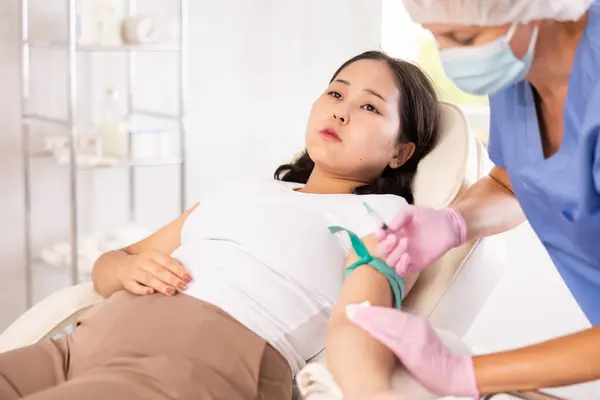 stock image Skilled middle-aged doctor in uniform giving patient injection into vein