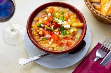 Cojondongo, typical summer dish from Extremadura with chopped tomatoes, pepper and eggs, day-old bread and dressing of garlic, olive oil and water, traditionally served cold in earthenware bowl clipart
