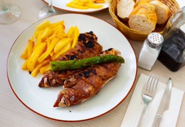 Meat dish with baked pork legs and french fries decorated with asparaguses clipart
