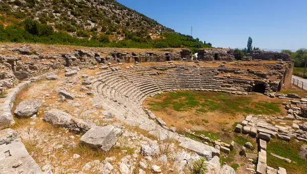 stock image Remains of Roman theater located on hillside in ancient settlement of Limyra in Antalya province of Turkey. View of stone seats of semicircle auditorium descending towards ruined stage..